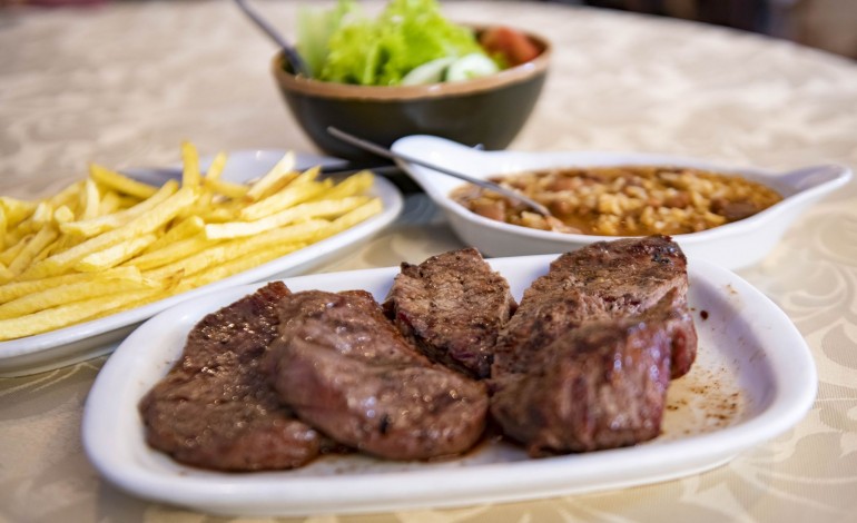 Na carne, uma peça grelhada, tenra e saborosa, acompanhada por arroz de feijão e batatas fritas da casa